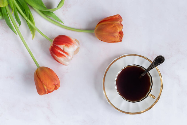 Alternative coffee substitute: a hot decaffeinated drink made from natural chicory, on the table in a white cup. Tulips grow nearby. Top view, copy space - Photo, Image