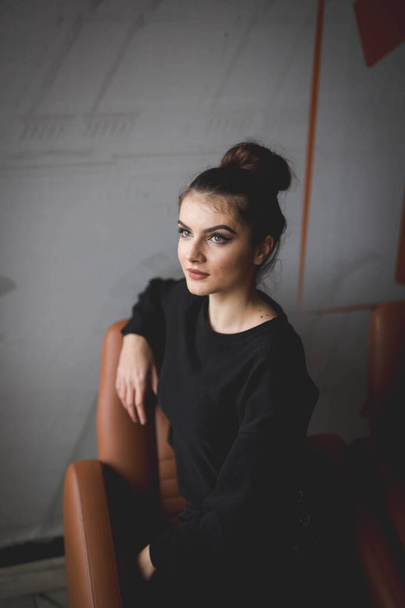 A shallow focus of a young brunette Caucasian female with light makeup sitting on a chair - Foto, immagini