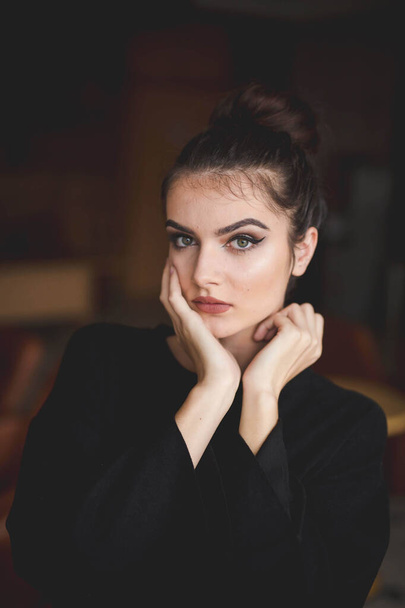 A shallow focus of a young brunette Caucasian female with simple makeup posing indoors - Фото, изображение