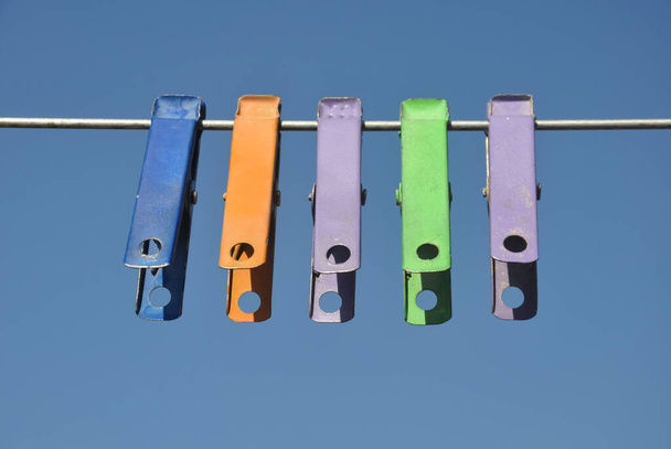 Vista frontale di clip di stoffa colorate appese su filo con cielo blu sullo sfondo - Foto, immagini