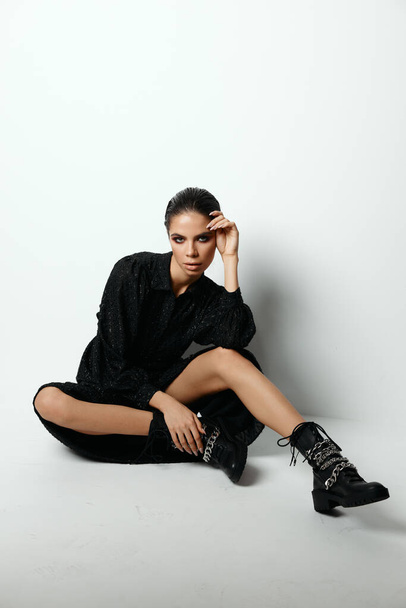 Frau sitzt auf dem Boden in einem schwarzen Kleid Mode-Studio-Stiefel - Foto, Bild