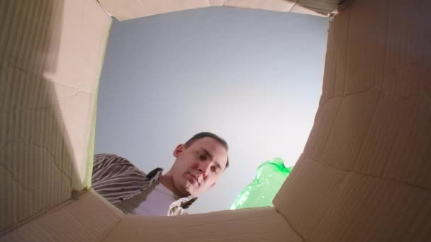 Video muže házet karton kontejner, spodní pohled - Záběry, video