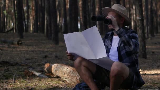 Young man resting, looking through binoculars and checking a map while hiking - Footage, Video