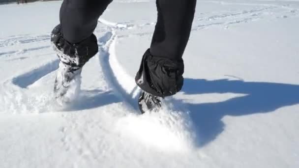 Vista in prima persona delle gambe negli scarponi da hockey che si muovono nella neve profonda. Neve che soffia gambe rotonde mentre si muove su un terreno ghiacciato. Rallentatore. - Filmati, video