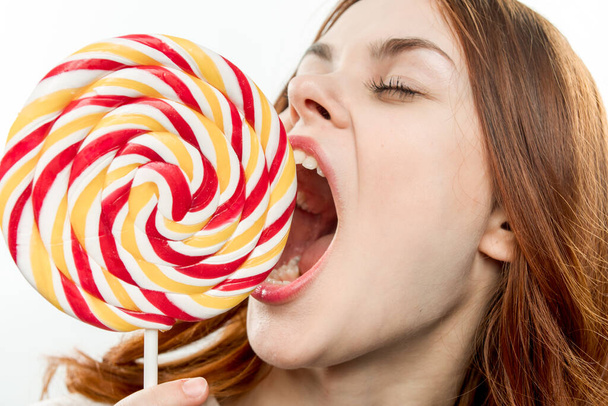 woman with round multicolored lollipop near face enjoying open mouth - Photo, image