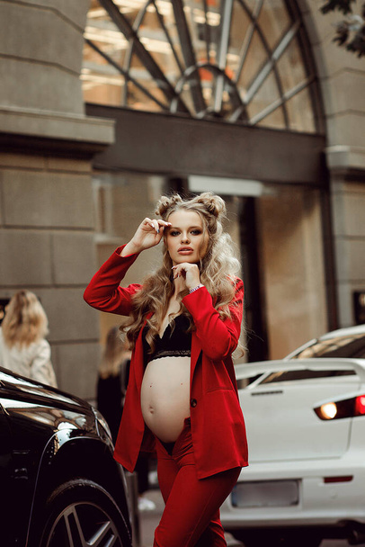 těhotná krása v červené procházky po městě mezi butiky ve městě - Fotografie, Obrázek
