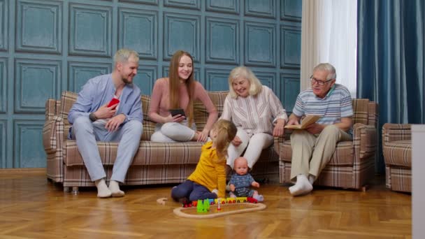 Ευτυχισμένος οικογενειακός ελεύθερος χρόνος πολλών γενεών στο σπίτι γονείς ζευγαριών και παππούδες που χαλαρώνουν στον καναπέ - Πλάνα, βίντεο