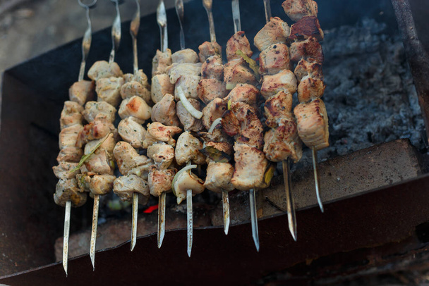 Marinaded pork meat pieces on skewers frying over bonfire. Kebab or traditional shashlik cooking with lot of smoke. - Photo, Image