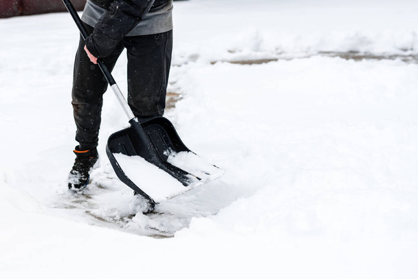 Woman cleaning snow from sidewalk and using snow shovel. - Photo, Image
