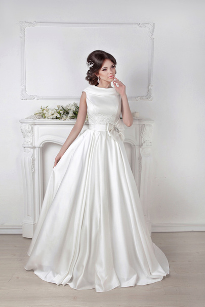 Beautiful bride woman posing in magnificent dress over white wal - Photo, image
