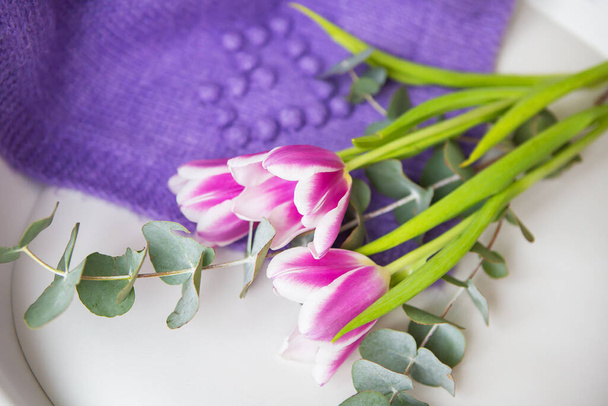Beautiful bouquet of purple tulips with eucalyptus on a white chair along with a purple sweater. Spring mood, 8 March. Postcard for the holiday - Photo, Image