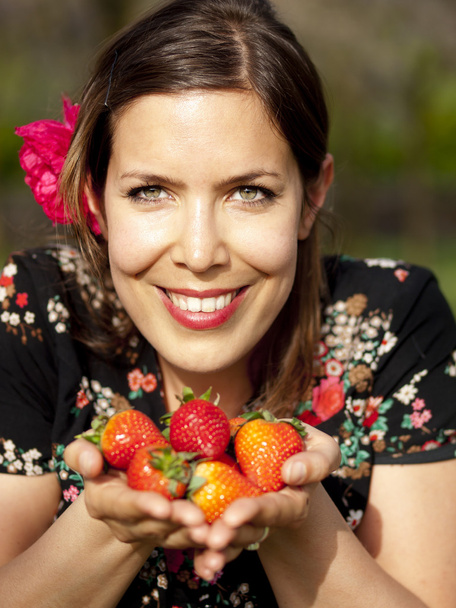Hermosa chica mostrando fresas en la primavera
 - Foto, Imagen