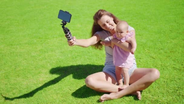 Mutter Bloggerin mit kleiner Tochter hat Spaß nimmt Videoblog auf grünem Gras auf. - Filmmaterial, Video