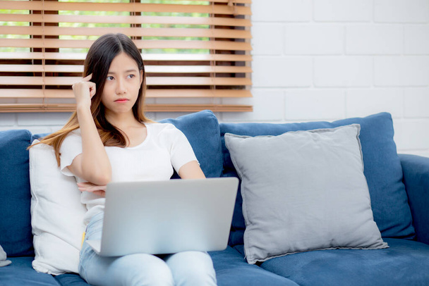 Mujer asiática joven trabaja en el ordenador portátil en el sofá en casa con frustrado y aburrido, chica independiente infeliz y cansado con sin éxito, molesto por el problema, el fracaso y el error, concepto de negocio. - Foto, Imagen