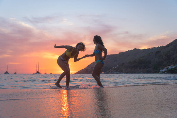 Due donne in posa bella sulla spiaggia. Durante l'epidemia del COVID-19 non molti turisti sulla spiaggia di Nai Harn. ma hanno ancora la gente del posto sulla spiaggia di Nai Harn Phuket Thailandia - Foto, immagini