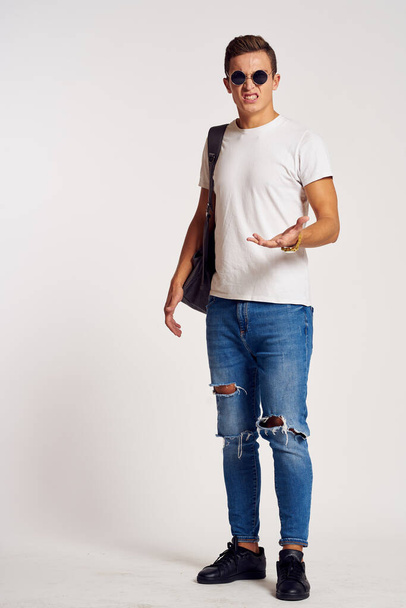 a man with a backpack on his back in jeans t-shirt full length sneakers and glasses on his face - 写真・画像