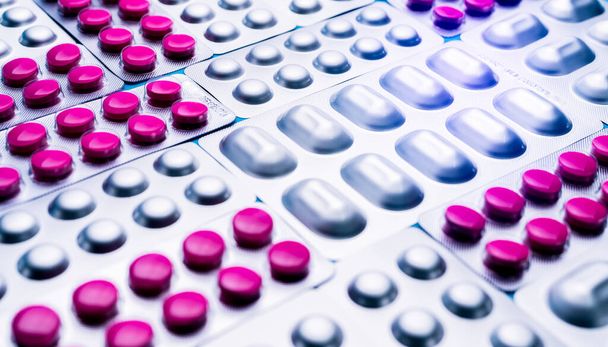 Pinkfarbene Tabletten in Blisterverpackung und silberne Alufolie in Tablettenverpackung. Pharmaindustrie. Pharmazeutische Produktion. Runde rosa Tabletten und lichtbeständige Verpackungen. - Foto, Bild