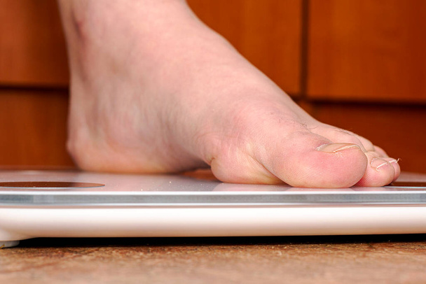 een persoon weegt zichzelf op een vloer elektronische schaal zet zijn voet op de schaal. Hoge kwaliteit foto - Foto, afbeelding