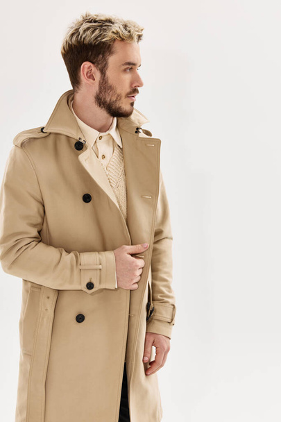 man met trendy kapsel in beige jas moderne stijl herfst kleding - Foto, afbeelding