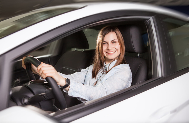 Join me for a drive. Attractive young woman sitting at the front seat of the car looking at camera - Photo, Image