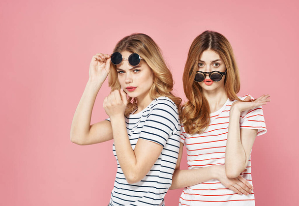 Дві жінки в сонцезахисних окулярах емоції спосіб життя модний одяг обрізаний погляд дружба
 - Фото, зображення