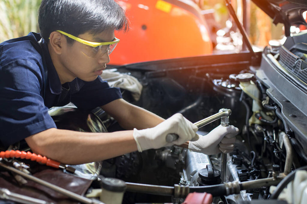 メカニックガレージで車のエンジンに取り組んで自動車整備士。修理サービス。自動車修理の概念 - 写真・画像