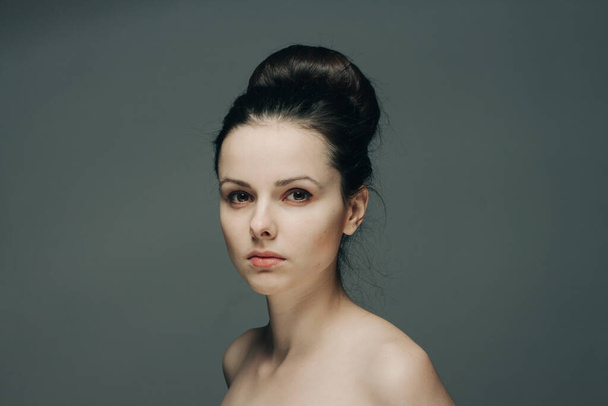 красивая женщина с голыми плечами на сером фоне модель прически - Фото, изображение