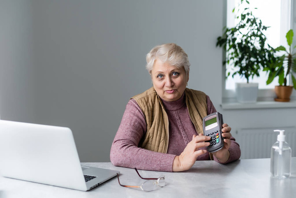 Ältere Frau sitzt während Quarantäne mit Laptop und Terminal - Foto, Bild