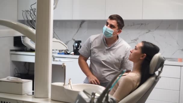 Un ortodontista discute con un paziente un piano di recupero facciale e riabilitazione dopo un incidente, guardando un'immagine a raggi X su uno schermo del monitor. - Filmati, video
