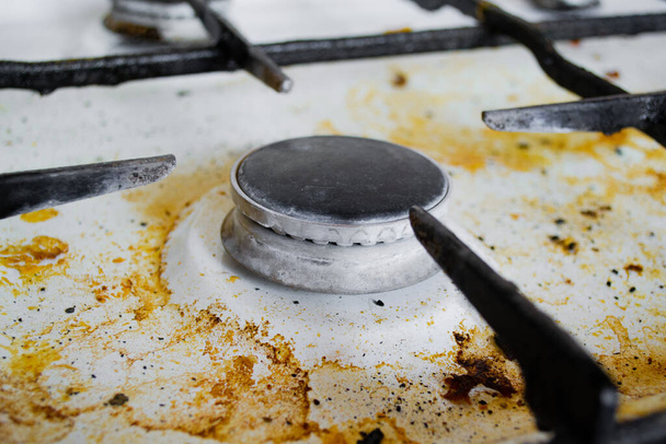 Close up de um fogão a gás branco muito sujo com estrias amarelas e manchas gordurosas. - Foto, Imagem