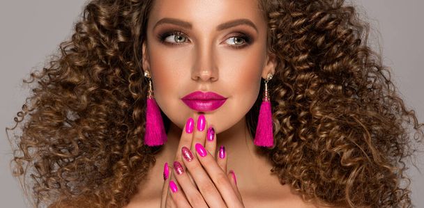 Piękny model dziewczyna z kręconymi włosami i różowymi paznokciami .Młoda kobieta z krótką falowaną fryzurą - Zdjęcie, obraz