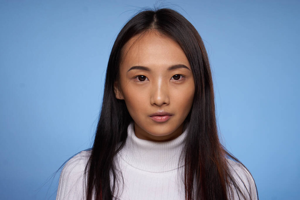 женщина азиатский внешний вид белый свитер обрезанный вид синий фон - Фото, изображение