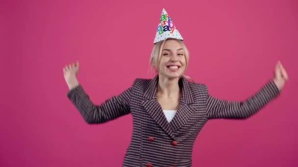 誕生日を祝う幸せな若い女性は彼女の頭にコーンを身に着けています - 映像、動画