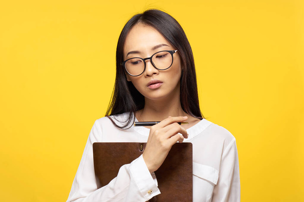 mujer asiática con cuaderno en mano aprendizaje estudiante amarillo fondo - Foto, imagen
