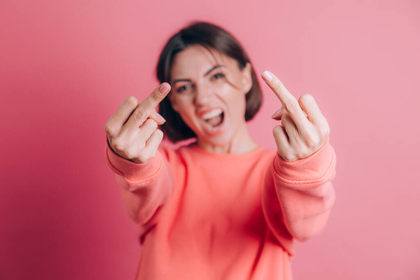 Mulher vestindo camisola casual no fundo mostrando o dedo médio fazendo má expressão, provocação e atitude rude - Foto, Imagem