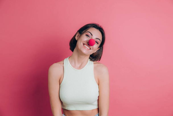 Donne su sfondo rosa piuttosto divertente e sorridente giovane donna che indossa naso da clown, umore da festa - Foto, immagini