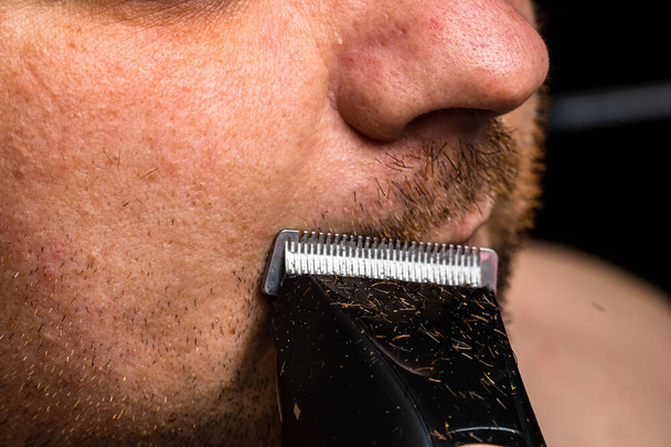 Homem barbear ou aparar a barba usando um cortador de cabelo - Foto, Imagem