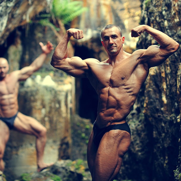 Two bodybuilders posing in a cave  - Photo, Image