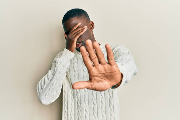Jonge Afro-Amerikaanse man draagt casual kleding die ogen bedekt met handen en doet stoppen met gebaar met droevige en angstexpressie. beschaamd en negatief concept.  - Foto, afbeelding