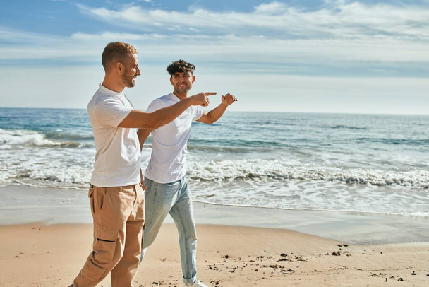 若いですゲイカップル笑顔幸せな歩行にザビーチ. - 写真・画像