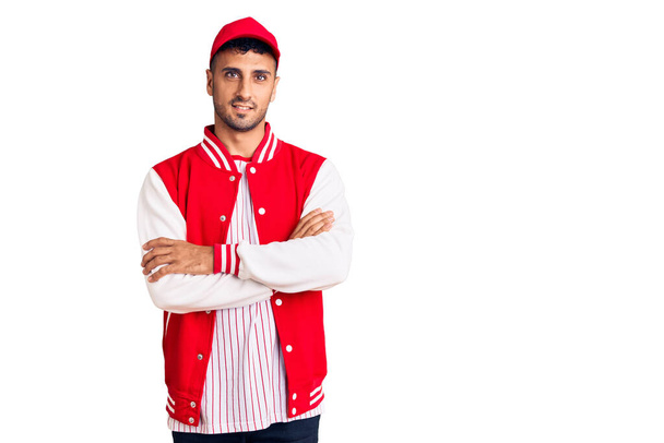 Jovem hispânico vestindo uniforme de beisebol rosto feliz sorrindo com os braços cruzados olhando para a câmera. pessoa positiva.  - Foto, Imagem