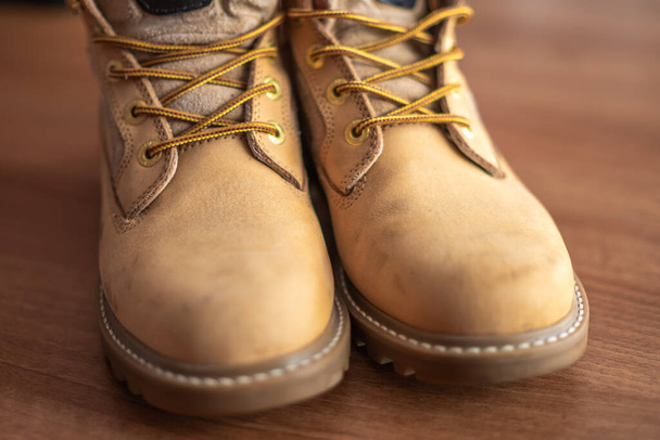 Detailní záběr pánských kožených bot na dřevěné podlaze se selektivním ostřením, mělkou hloubkou pole a bokeh - Fotografie, Obrázek