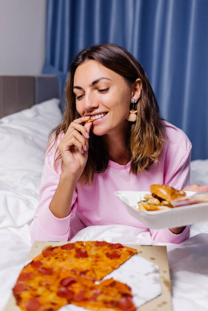 Frau isst Fast Food von Lieferung auf Bett im Schlafzimmer - Foto, Bild