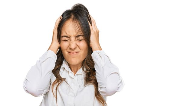 Jonge brunette vrouw draagt casual kleren die lijden aan hoofdpijn wanhopig en gestrest omdat pijn en migraine. handen op het hoofd.  - Foto, afbeelding