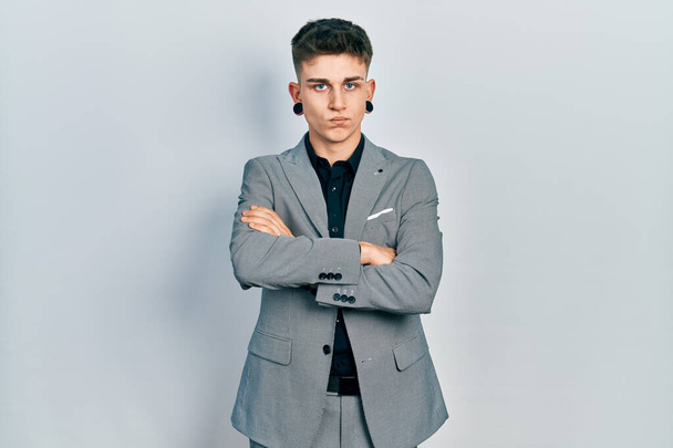 Young caucasian boy with ears dilation wearing business jacket skeptic and nervous, disapproving expression on face with crossed arms. negative person.  - Photo, Image