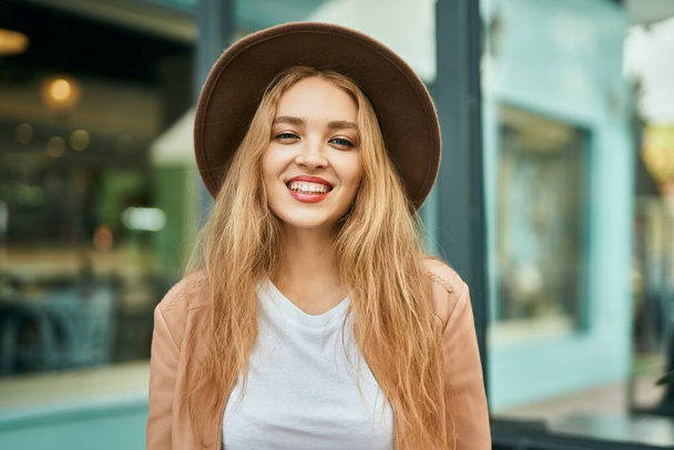 Молода блондинка посміхається щаслива стоячи в місті
. - Фото, зображення