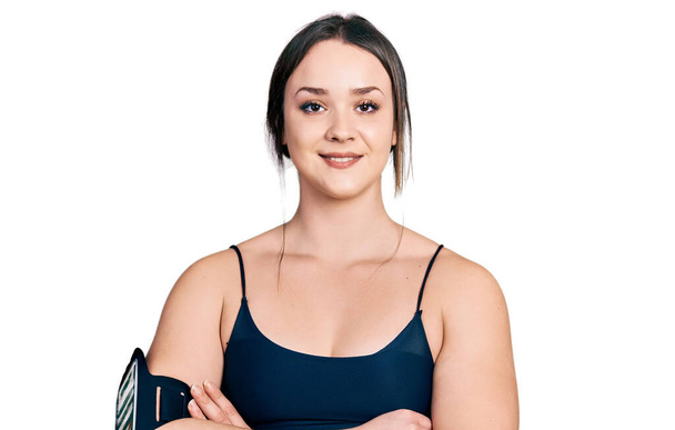 Młoda Latynoska kobieta w odzieży sportowej uśmiechnięta z skrzyżowanymi ramionami patrząca w kamerę. osoba pozytywna.  - Zdjęcie, obraz