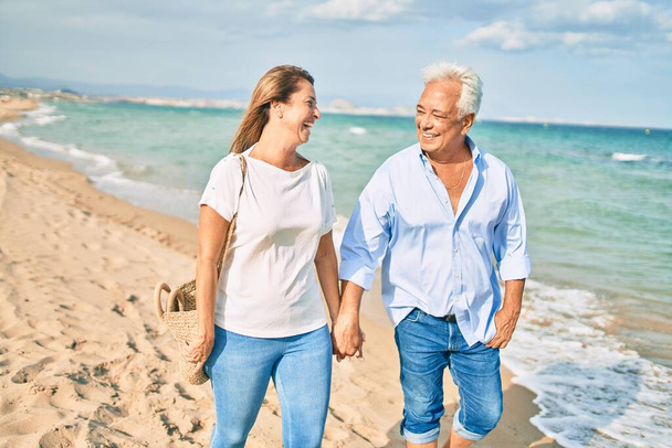 Испанская пара средних лет, улыбающаяся счастливая прогулка по пляжу. - Фото, изображение