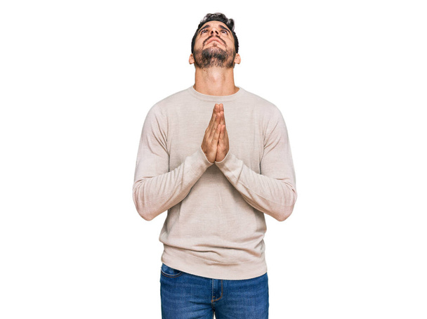 Young hispanic man wearing casual clothes begging and praying with hands together with hope expression on face very emotional and worried. begging.  - Фото, изображение