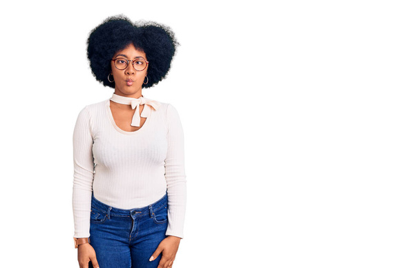 Young african american girl wearing casual clothes and glasses making fish face with lips, crazy and comical gesture. funny expression.  - Foto, Imagem